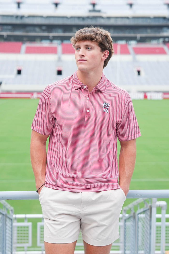 Person wearing a pink polo shirt with a logo on a sports field