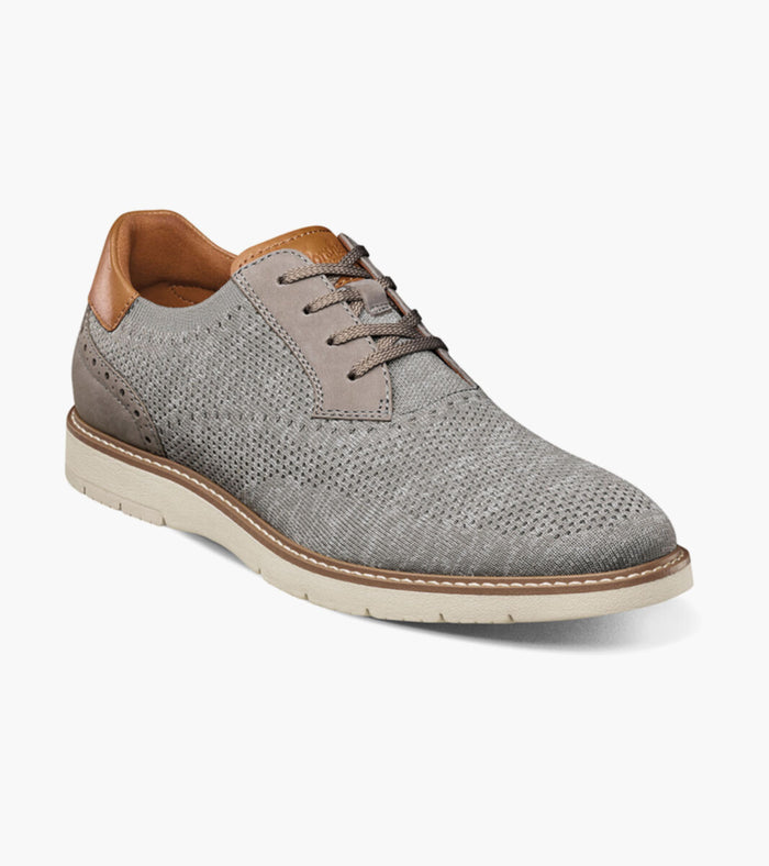 A casual men's shoe with a navy blue knit textile upper and nubuck detailing, featuring a white rubber outsole and tan accents.