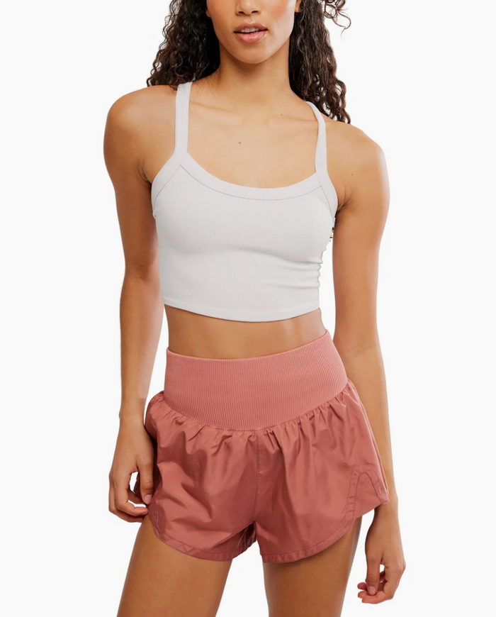 Woman wearing a white tank top and pink shorts on a white background