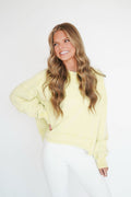 Woman wearing a light yellow sweater against a white background