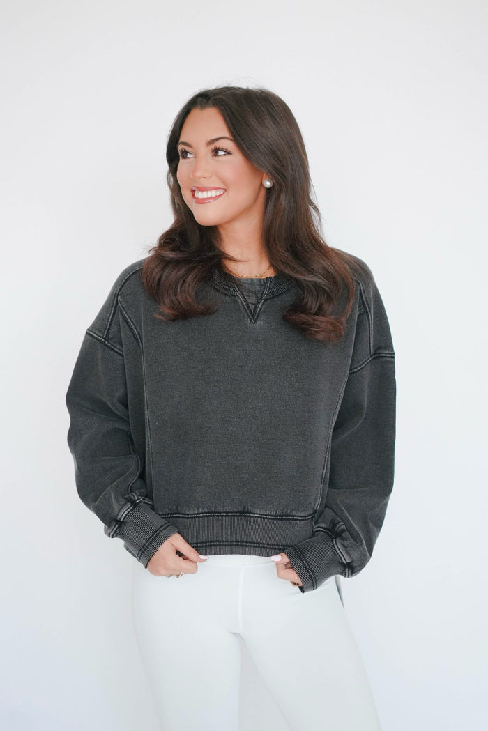 Woman wearing a dark gray sweatshirt against a white background