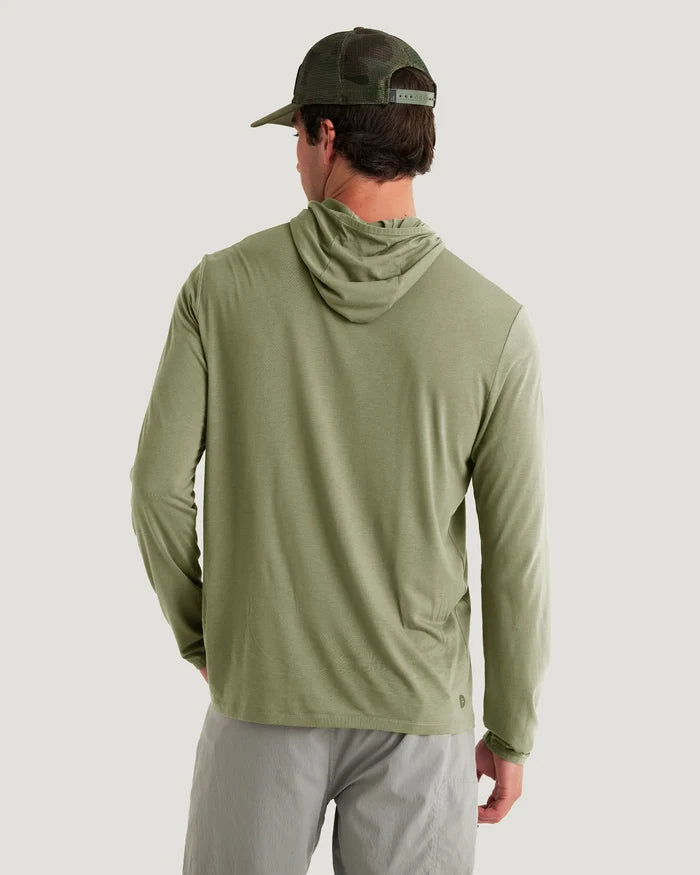Back view of a male wearing a muted green hoodie with grey sweatpants.