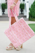 Person holding a pink and white patterned tote bag outdoors.