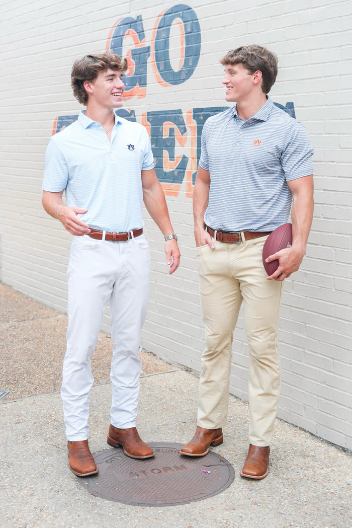 Two men standing outdoors with a wall in the background displaying 'GO TIGERS'.