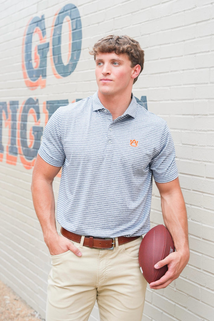Man holding a football against a wall with 'GO' and 'RIG' painted on it