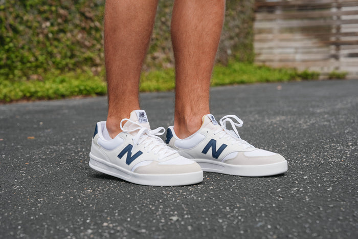 A pair of New Balance CT300 sneakers with a white mesh fabric, leather & suede upper, and a rubber sole.